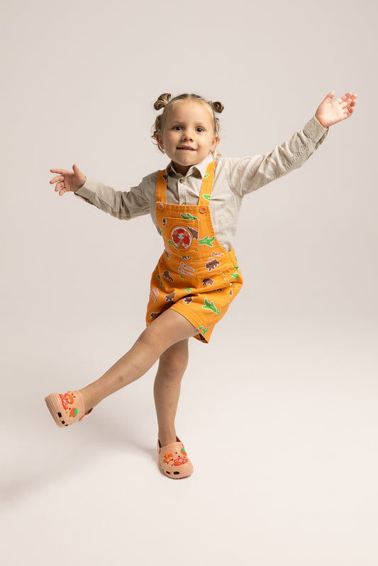 Child wearing Emma Memma orange overalls outdoors